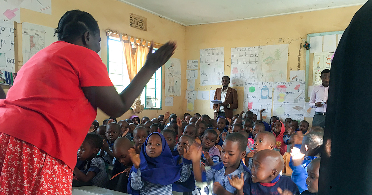 A teacher stands in front of a classroom of children