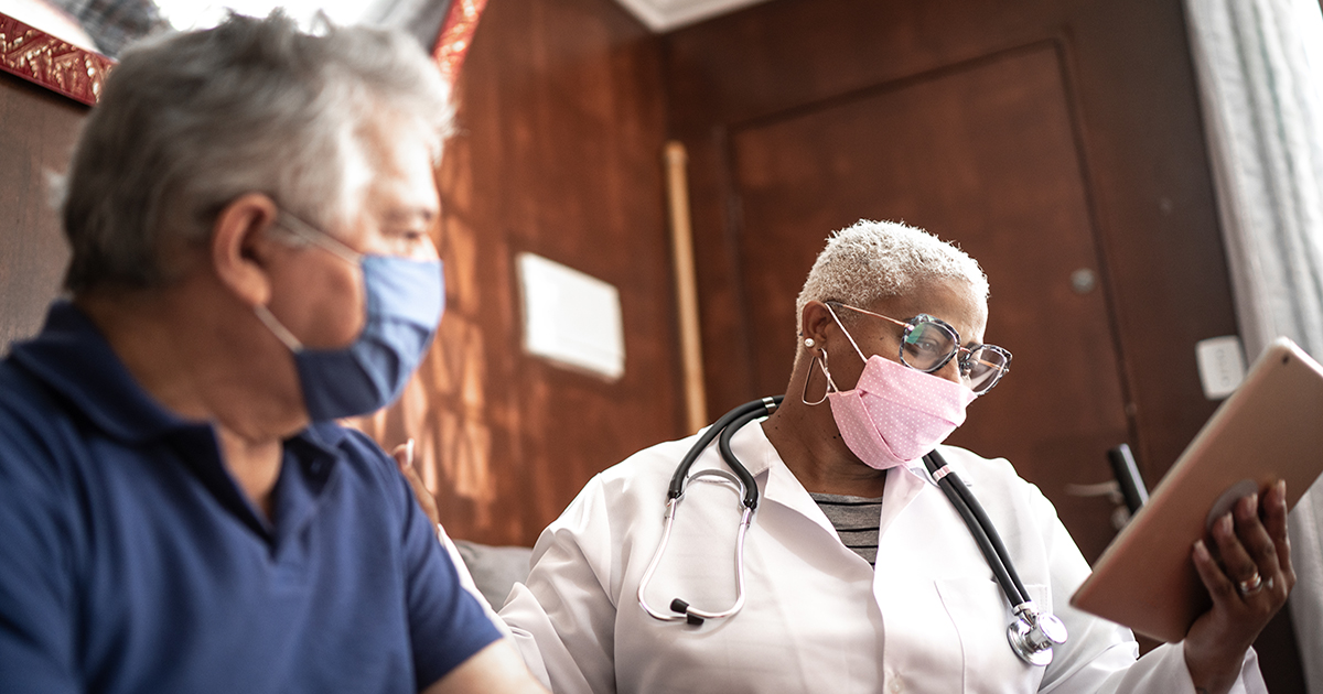 Doctor talking to senior male patient in a home visit.