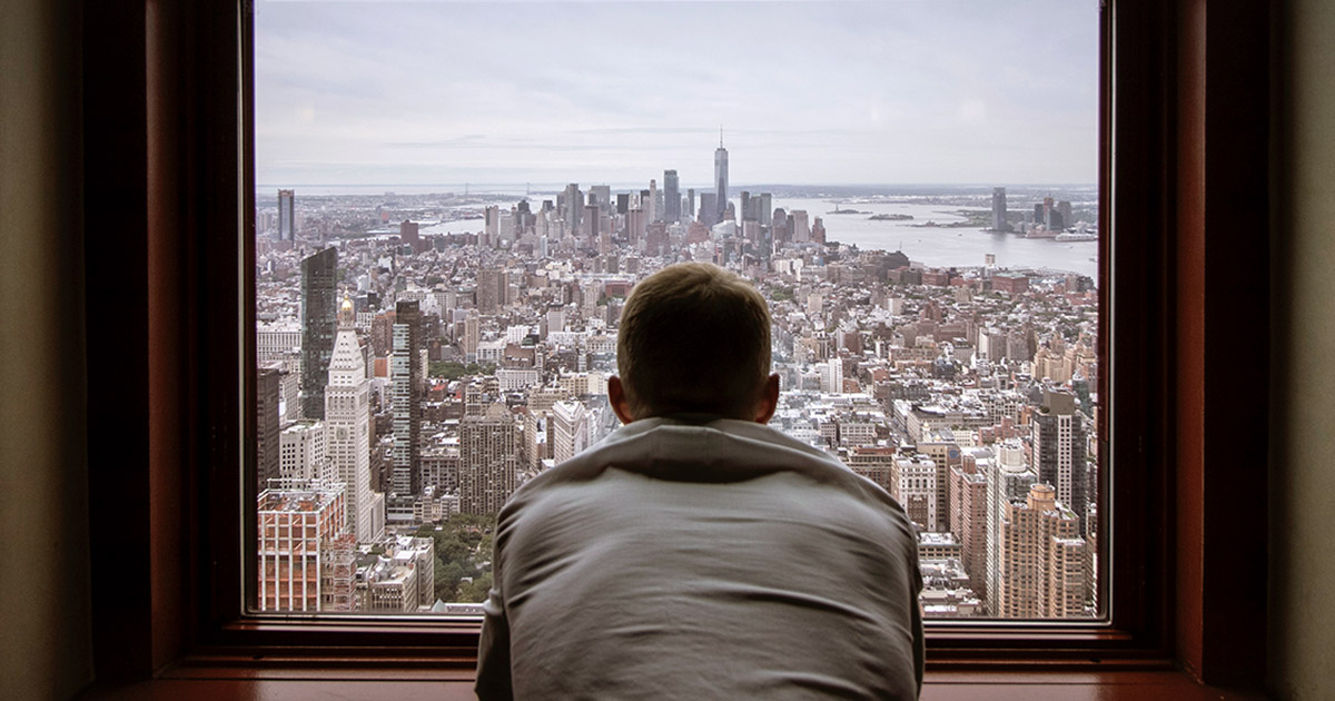 Man looking out the window at city buildings