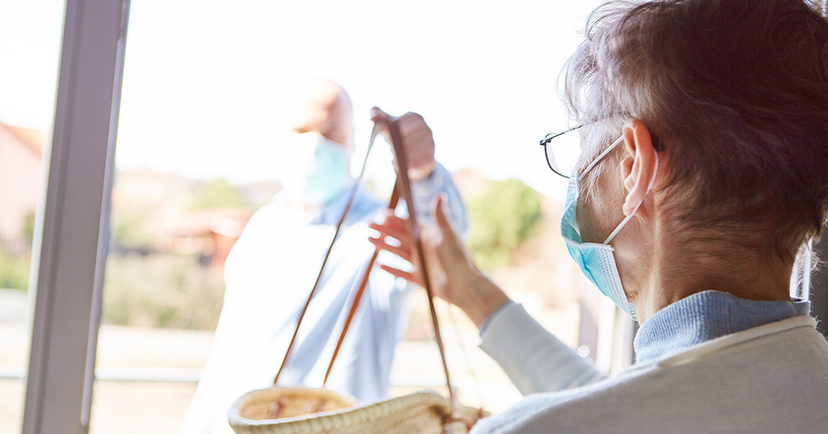 Elderly woman in quarantine with face mask gets food delivery to her home