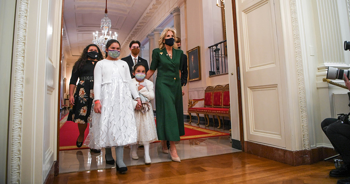 First Lady Dr. Jill Biden entering the East Room of the White House with a group of Hidden Helpers.