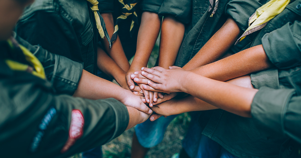 Scouts in a circle stacking their hands on top of each other