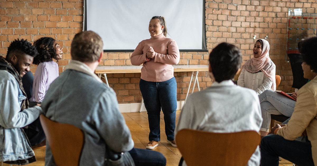  A young woman with special needs talks in a meeting.
