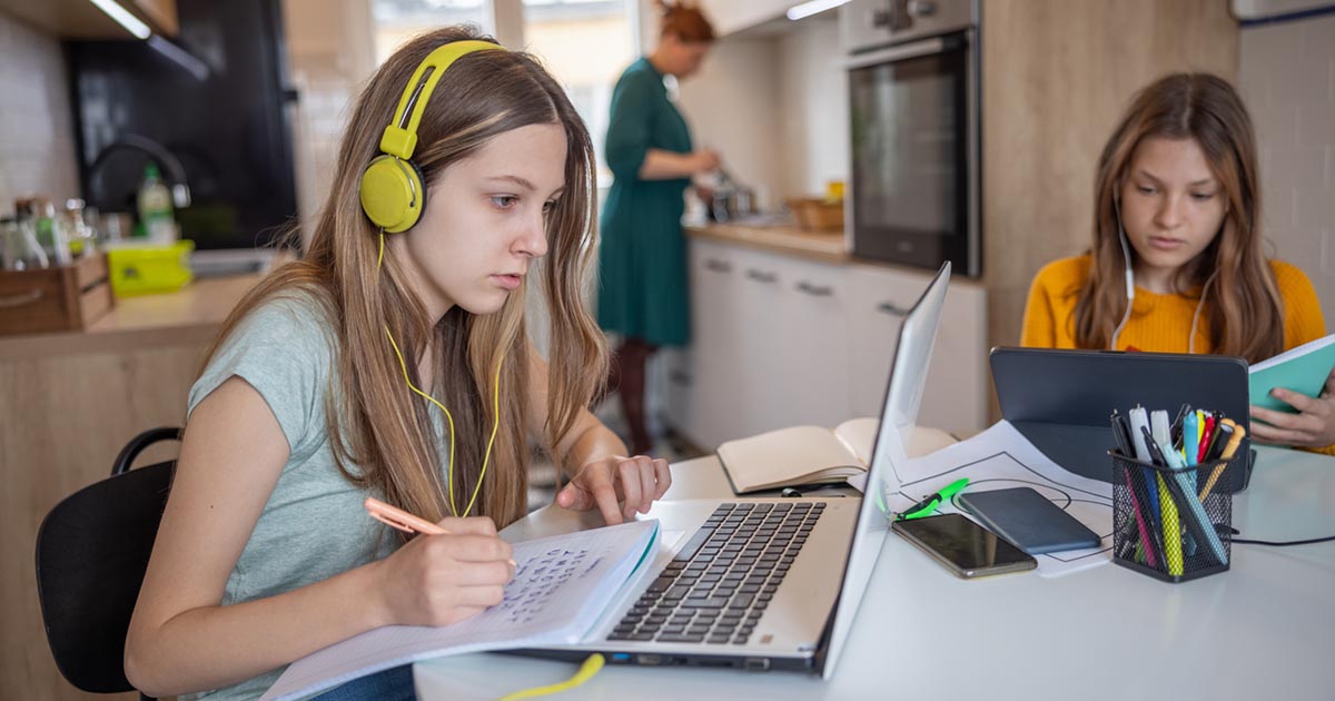 a child wearing headphones and writing on a notebook