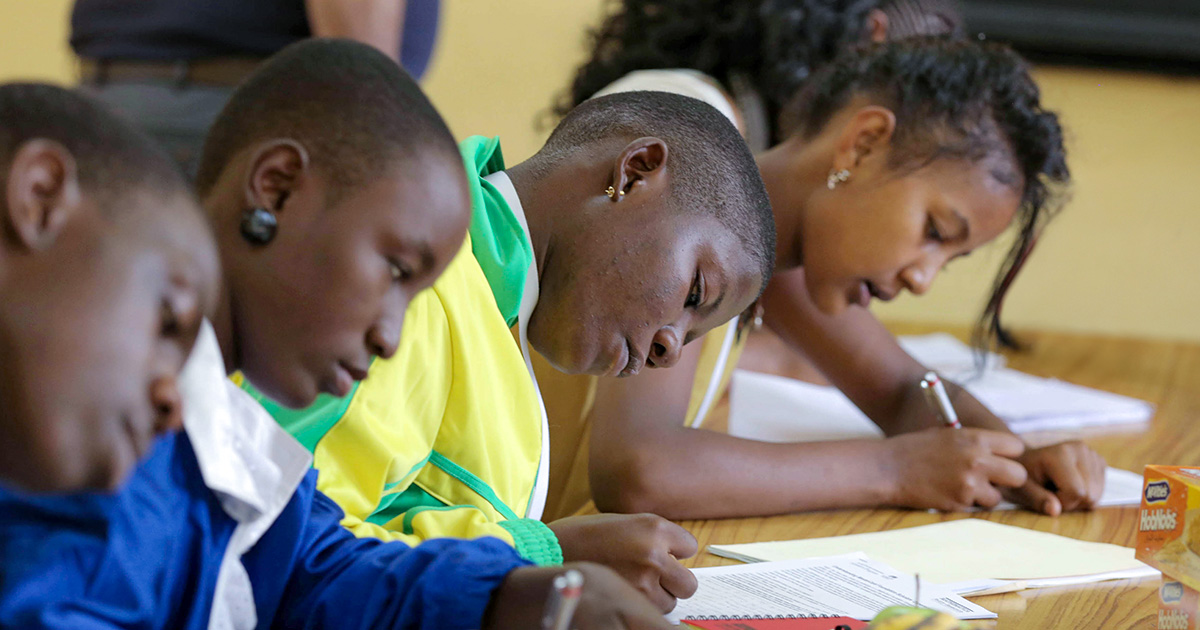 Four schoolchildren writing in a classroom.