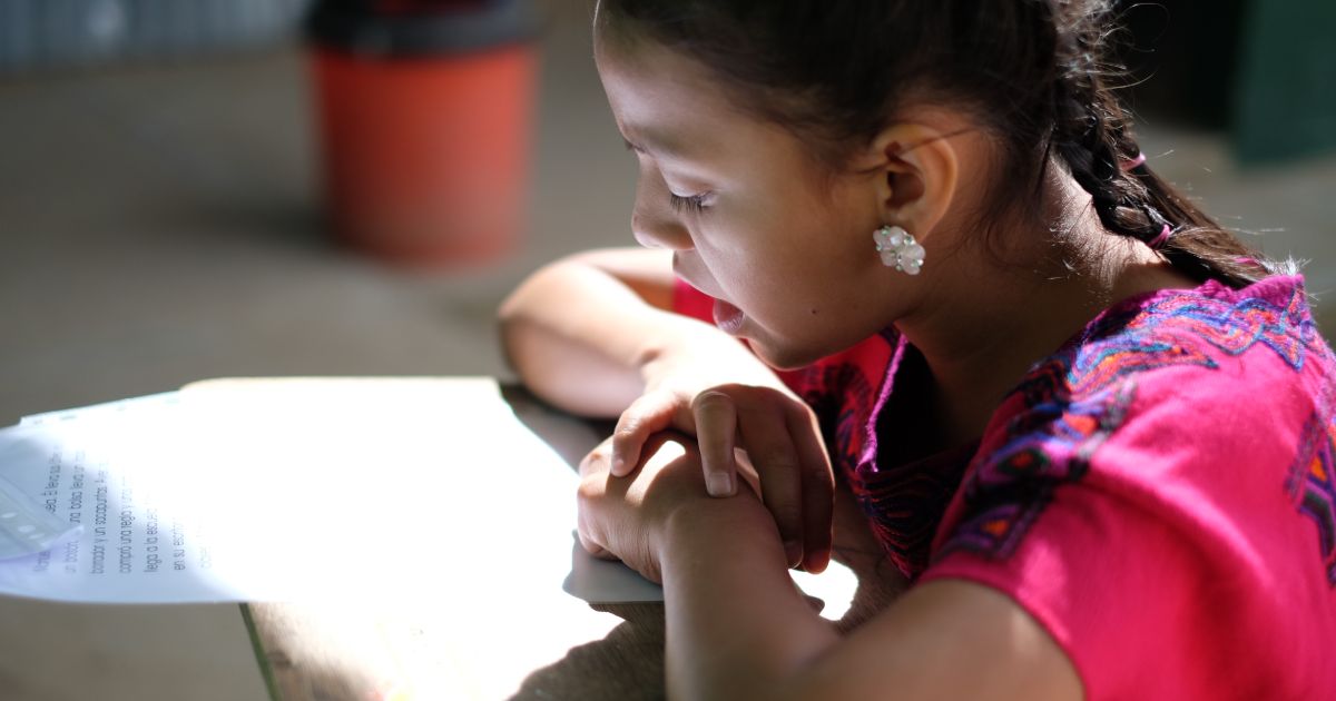 A student in Guatemala practices her reading
