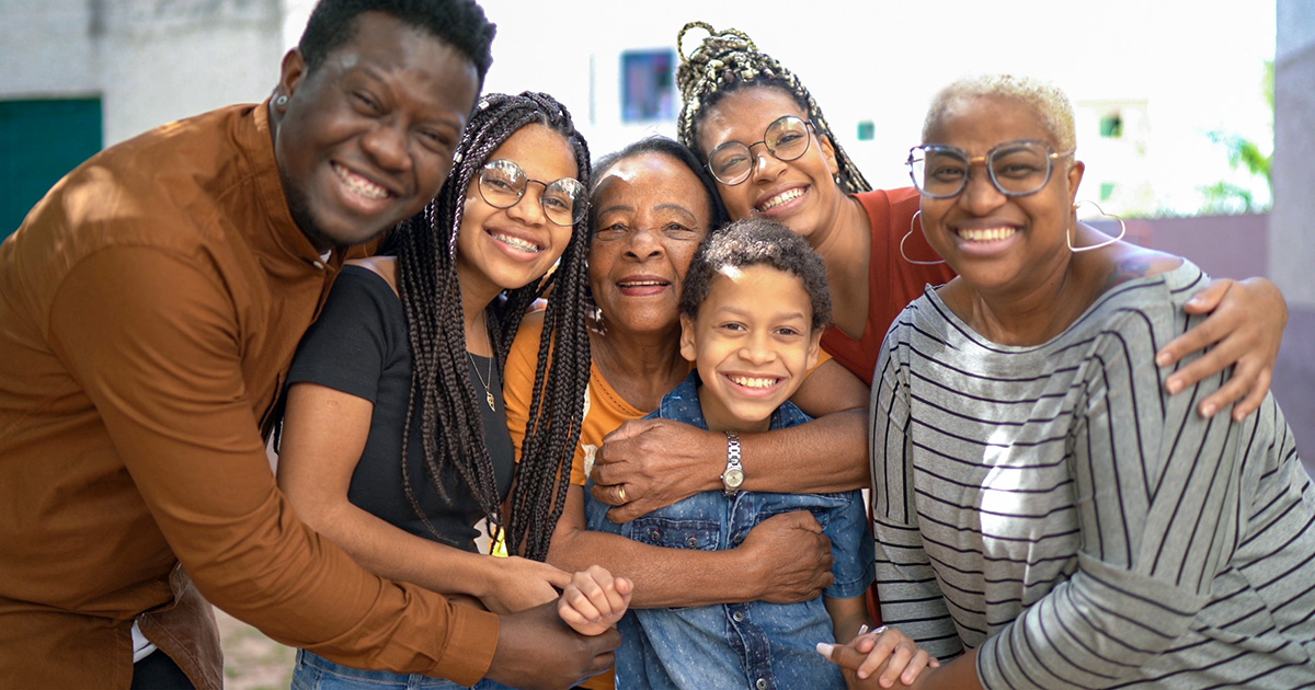 Smiling multigenerational family of six embracing and posing together for a group photo.