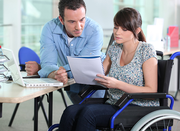 woman in a wheelchair working with male colleague woman in a wheelchair working with male colleague