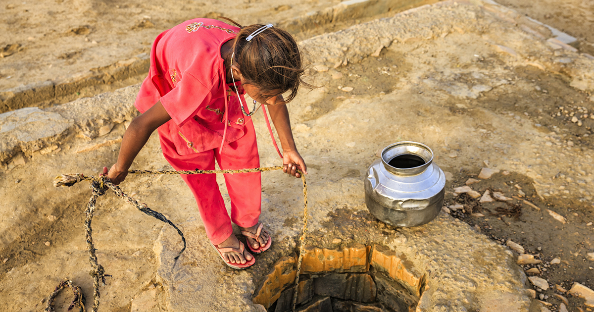Indian young girl drawing water from a well.