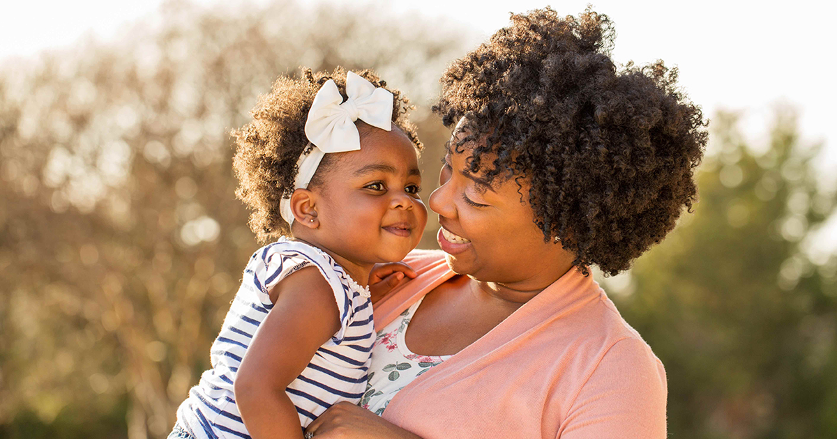 A parent holding a child, both smiling. 