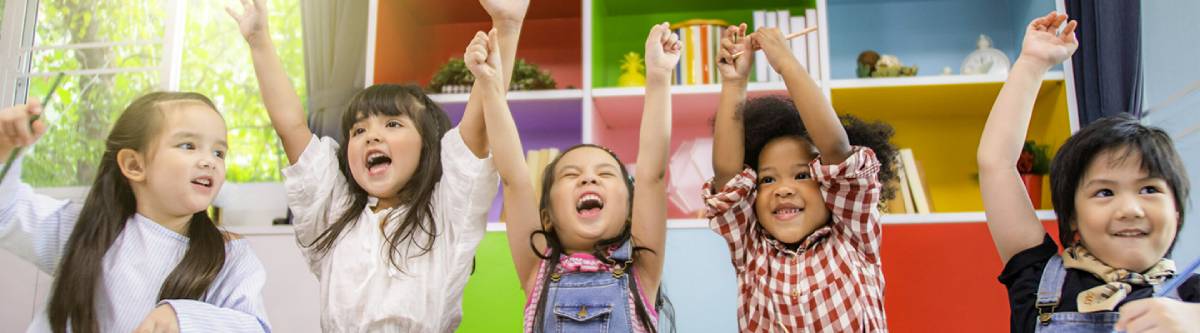 5 pre-school to kindergarten aged children raising their hands in the air.