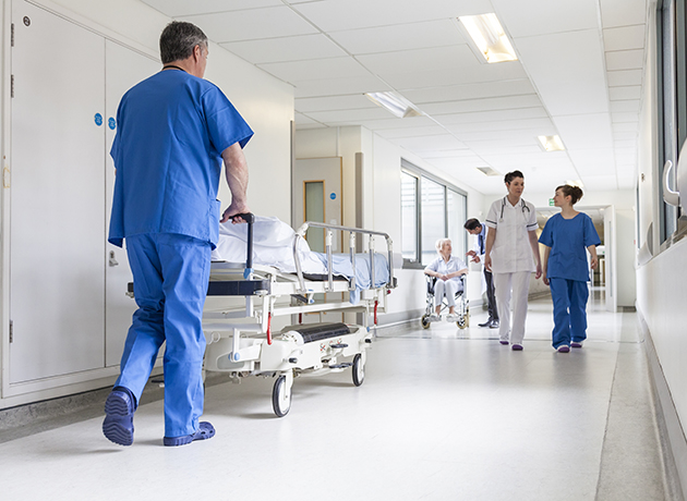Male nurse wheeling gurney down hall Male nurse wheeling gurney down hall