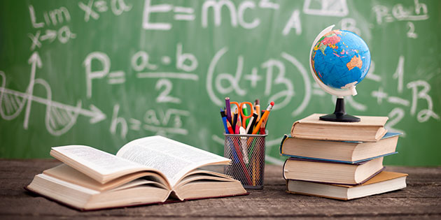 Books and a globe on a desk in a classroom. Books and a globe on a desk in a classroom.