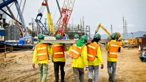 construction workers carrying beams
