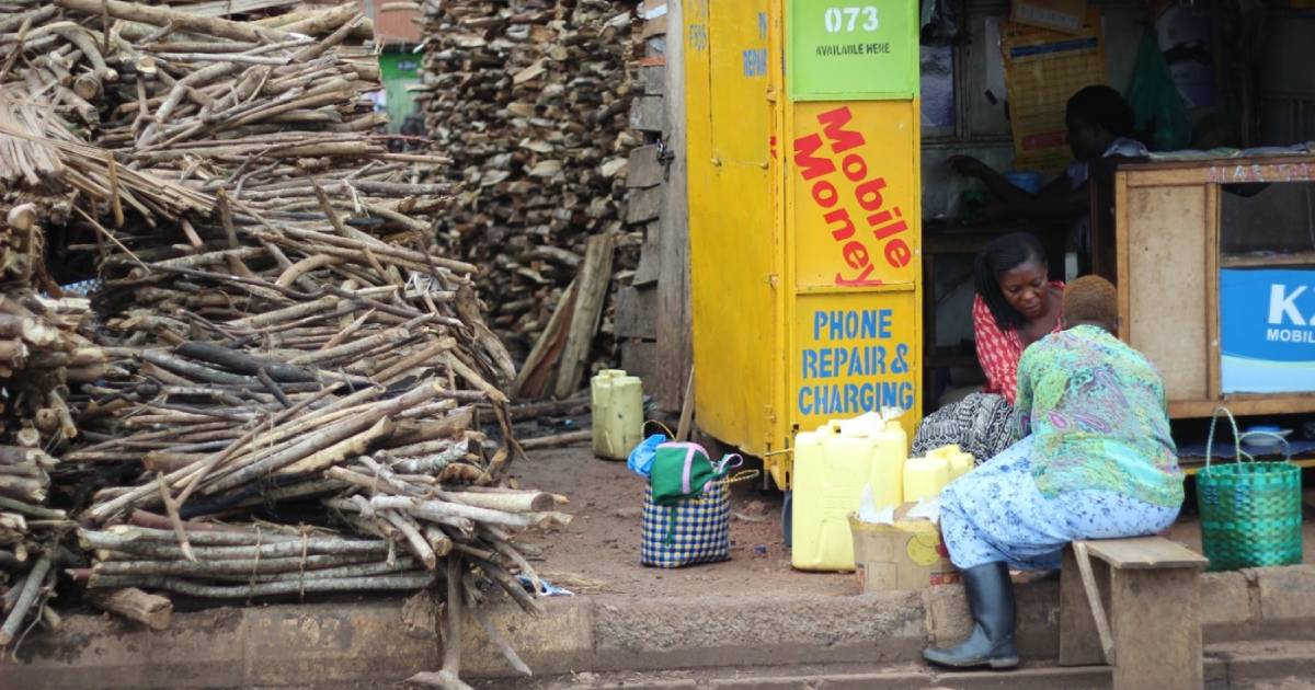 Two women talking on a bench outside a phone repair store.