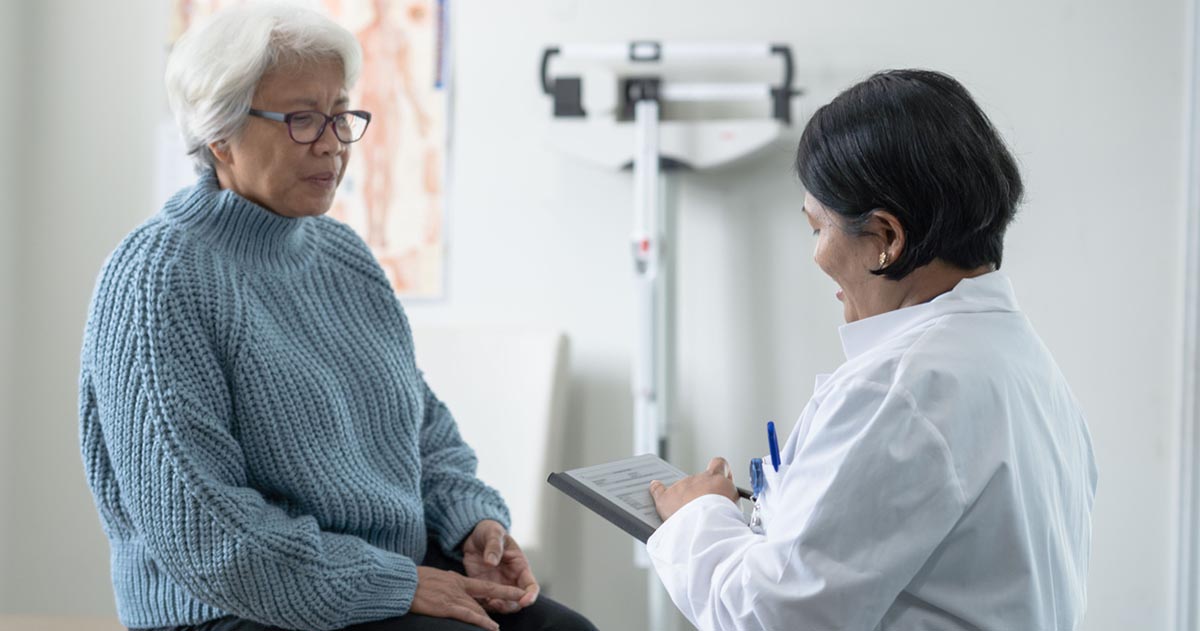 An elderly patient listens to a medical professional.