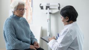 An elderly patient listens to a medical professional.