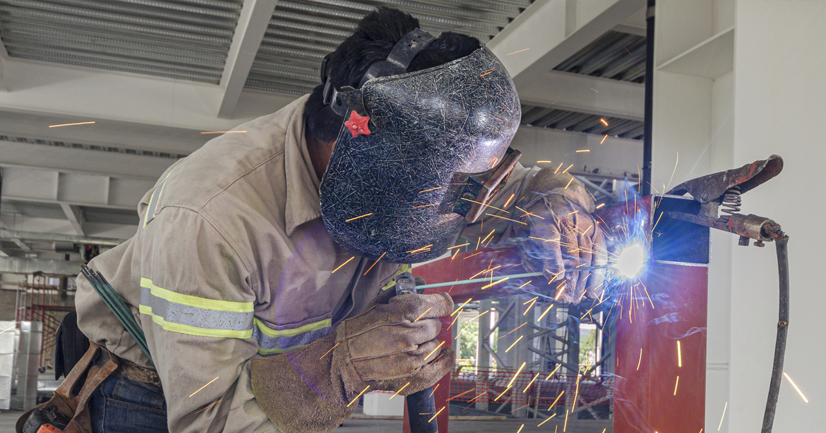 A welder soldering a big metal column.