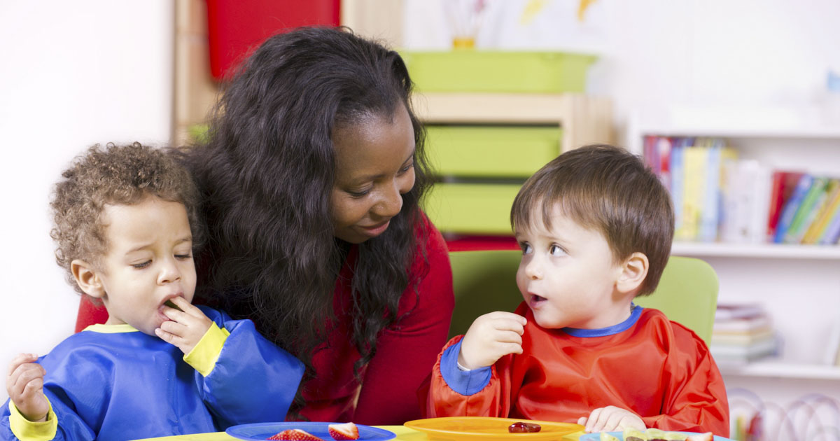 An adult smiling at two toddlers