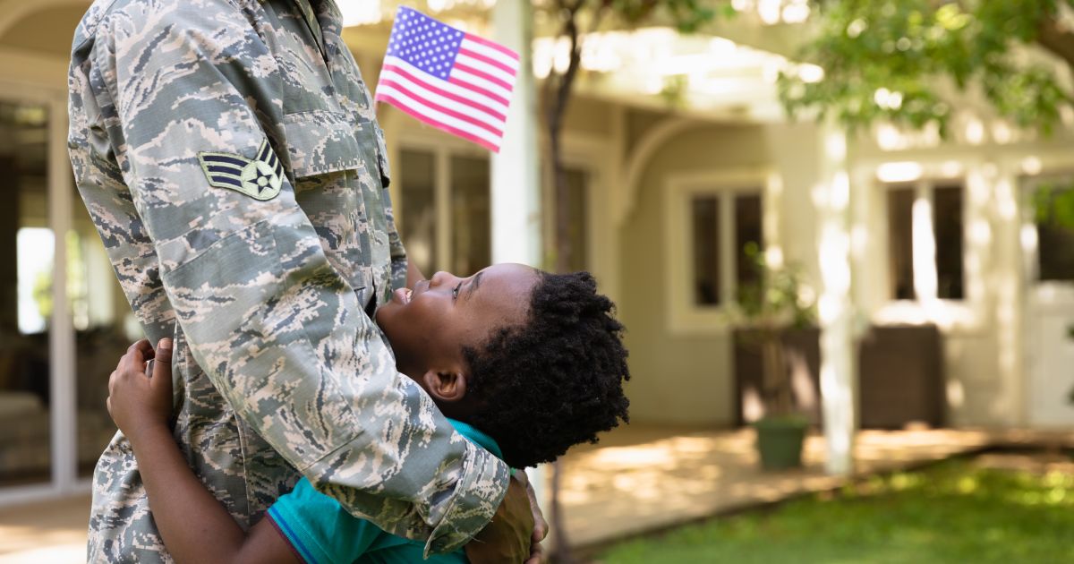 A child hugs and smiles up at a uniformed parent 