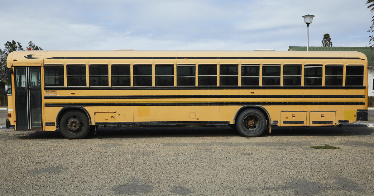 a yellow school bus parked on gravel